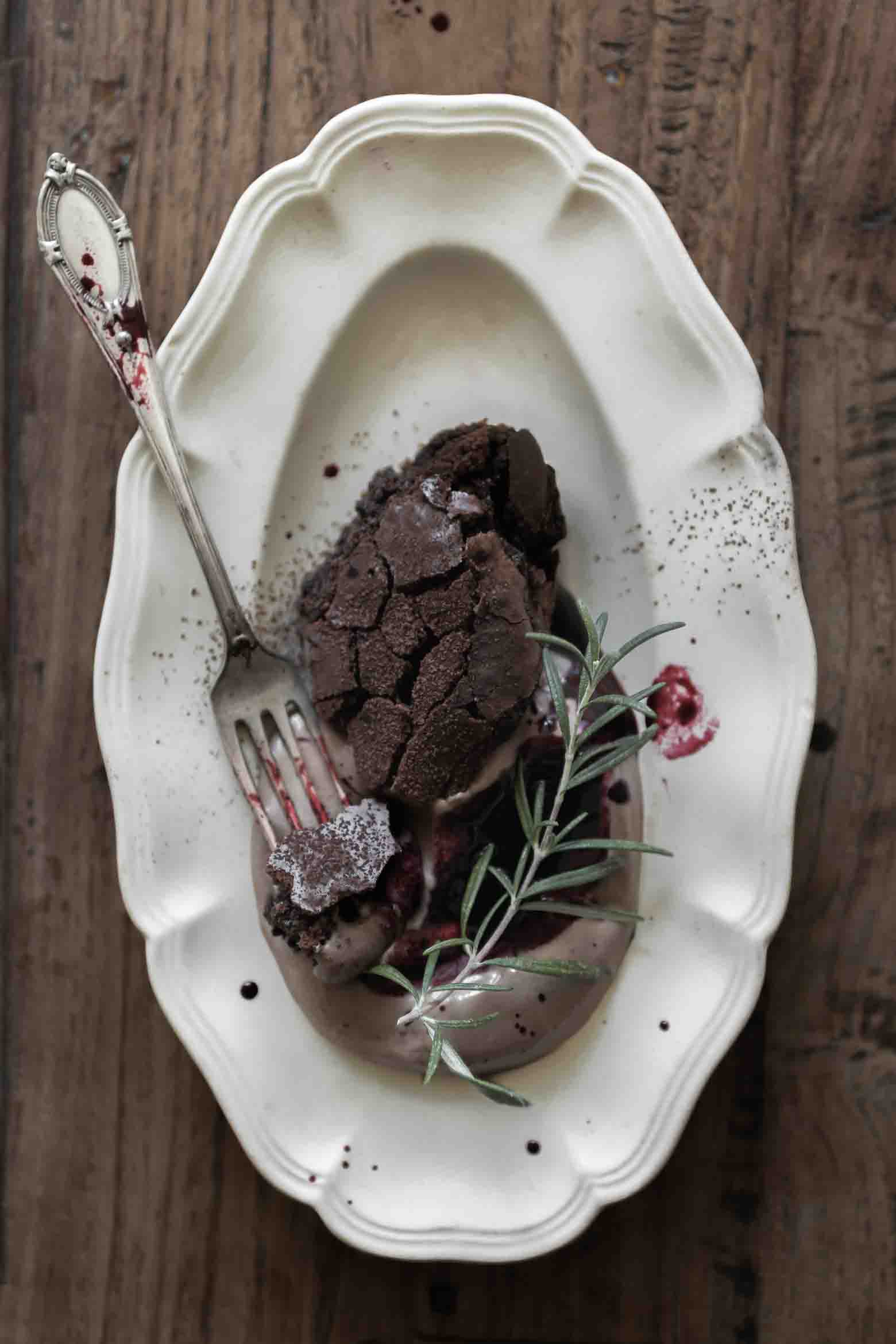 Deconstructed dark chocolate brownie with light chocolate mousse, black currant-rosemary syrup and fresh rosemary on a vintage plate.