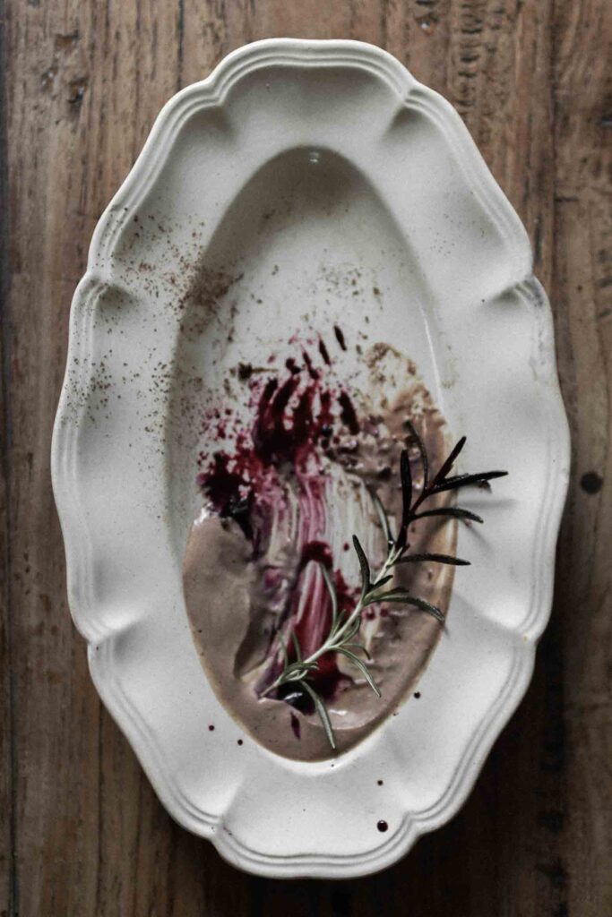 Chocolate mousse and black currant-rosemary syrup on a vintage plate with fresh rosemary.